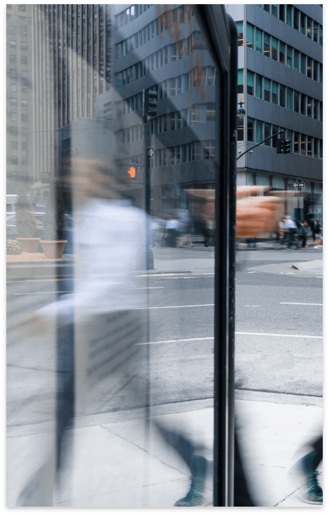 Blurred cityscape and pedestrians reflected in glass.