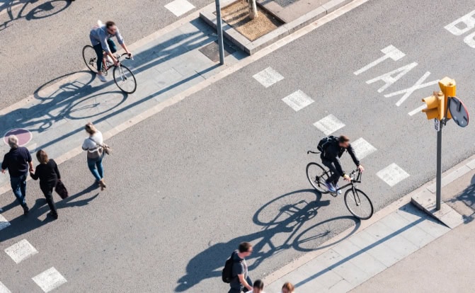 Cyclists and pedestrians crossing city street, overhead view.