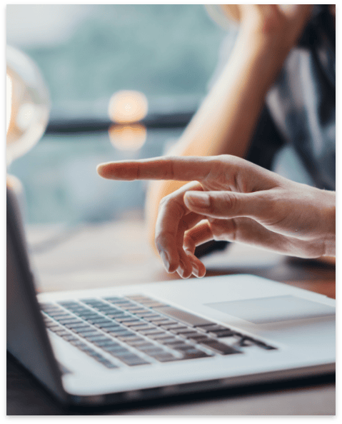 Laptop screen with a person pointing at it, close-up of hand and device.