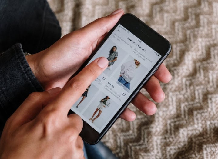 Women shopping online on smartphone for clothing.