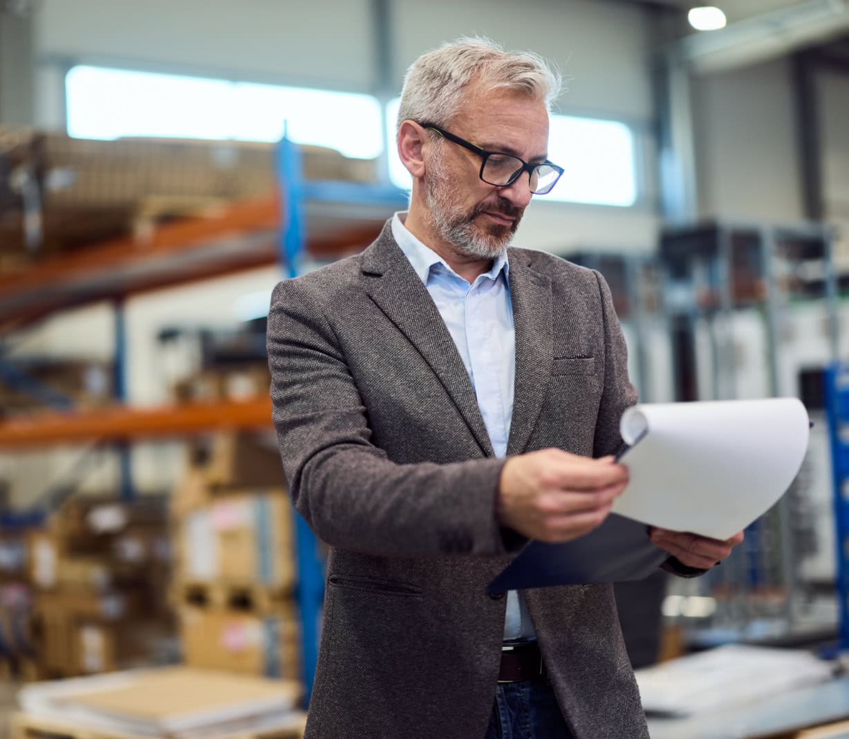 Warehouse manager reviewing documents in storage facility, industrial environment, CEO business professional, checking inventory, logistics, corporate, productivity, supply chain, success, management.