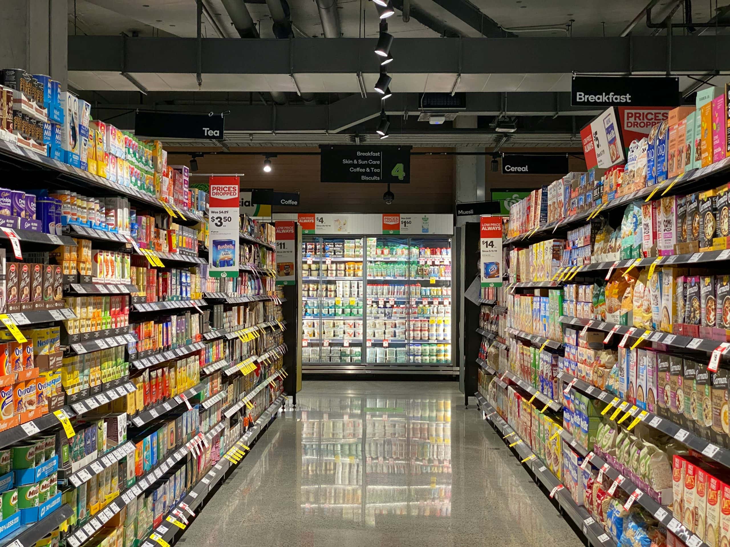 Brightly lit grocery store aisle featuring cereal, snacks, and dairy products on organized shelves.